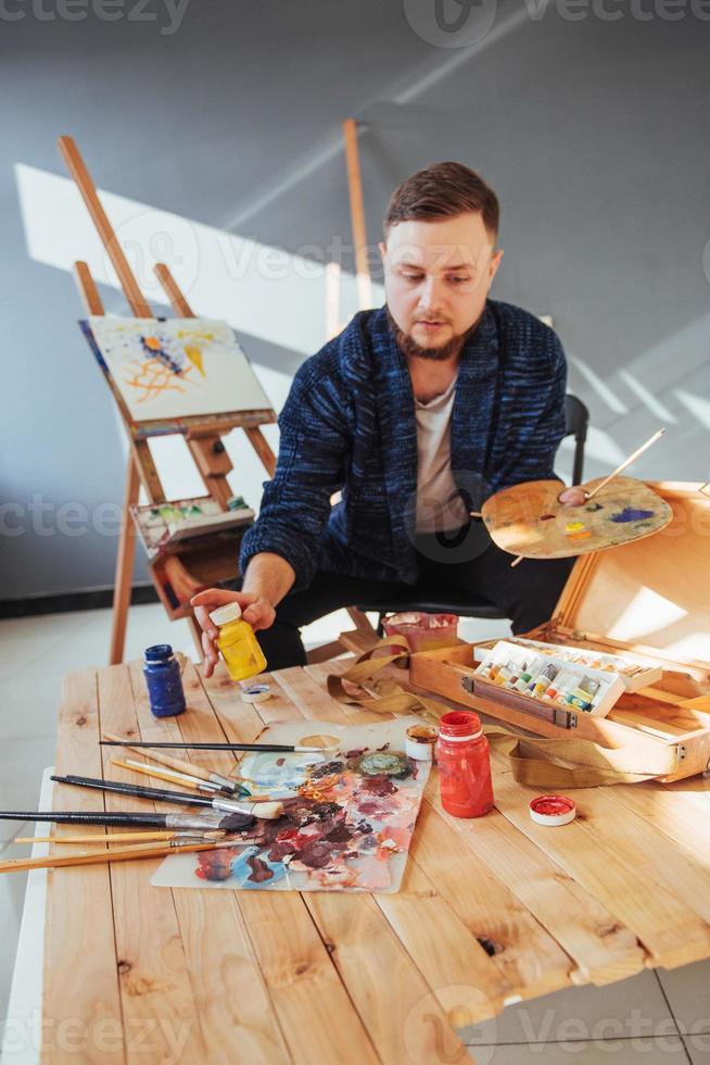 ontworpen door kunstenaar man afwerking van zijn meesterwerk houdt een borstel in de hand. foto