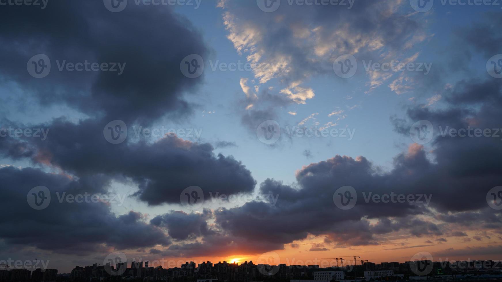 het prachtige uitzicht op de zonsondergang met het silhouet en de kleurrijke wolkenlucht in de stad foto