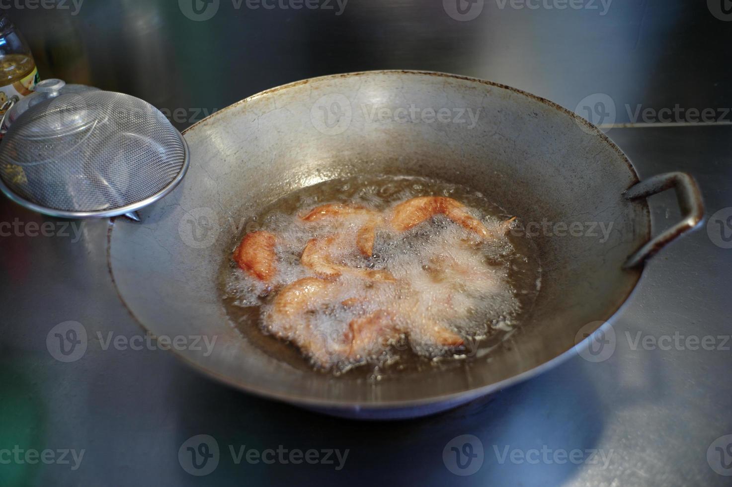 selectieve focus op veel stukjes kippenvleugels gefrituurd in de gekookte plantaardige olie. foto