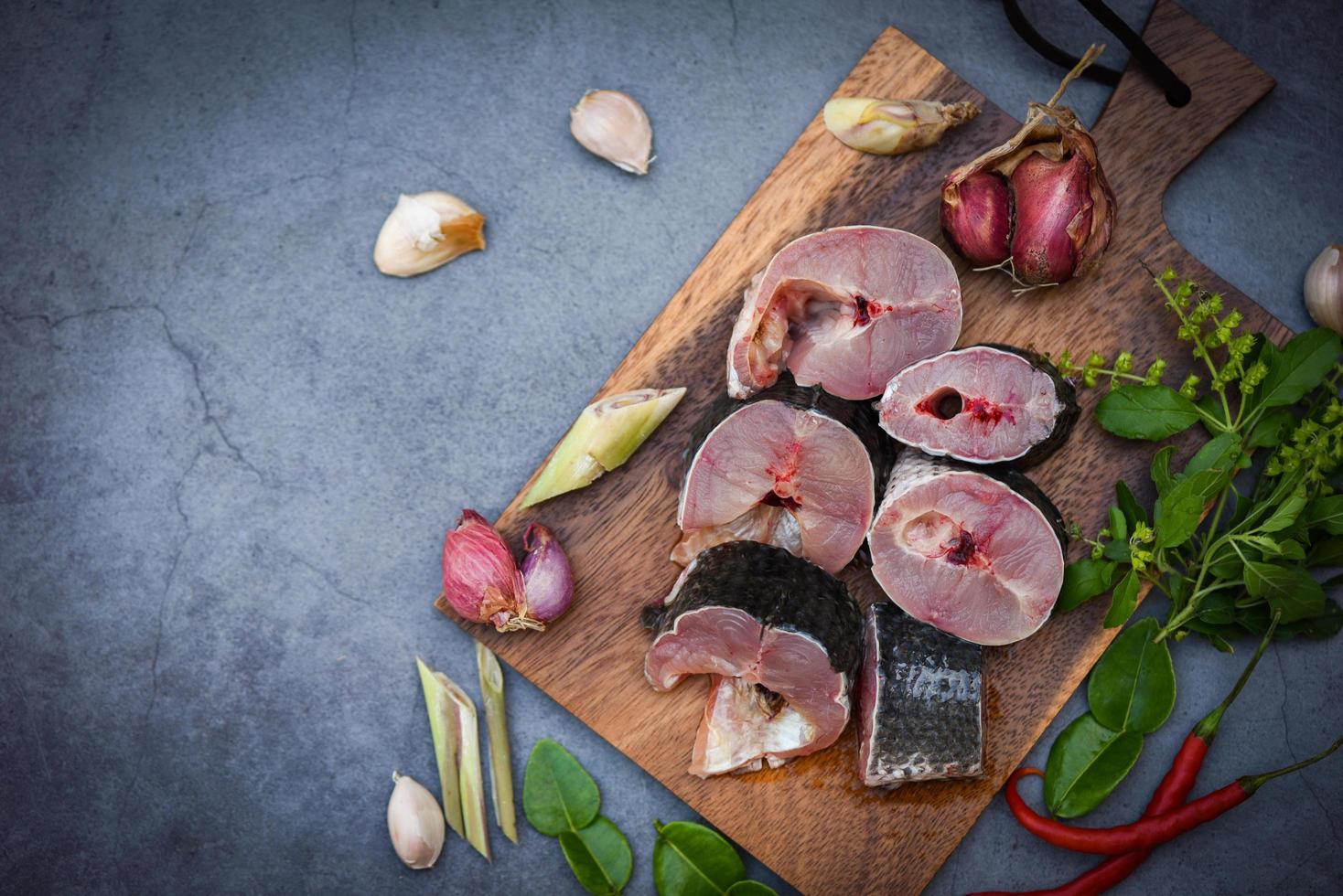 snakehead vis voor het koken van voedsel, gestreepte snakehead vis gehakt met ingrediënten kruiden en specerijen op houten snijplank en tafel keuken achtergrond, verse rauwe snakehead vis menu zoetwatervis foto