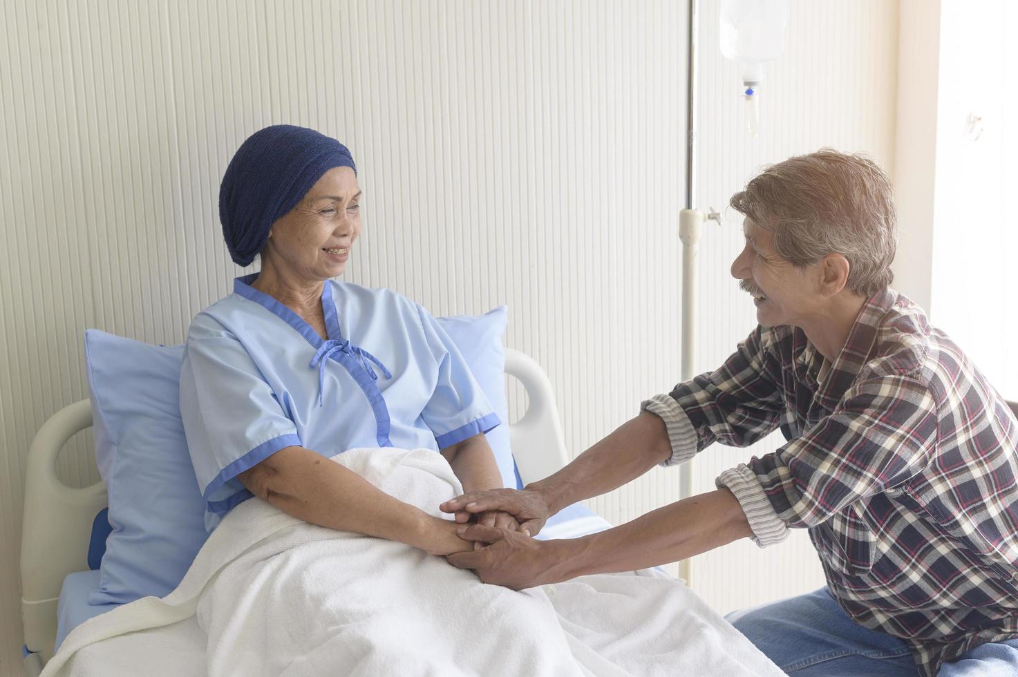 senior man op bezoek bij kankerpatiënt vrouw met hoofddoek in ziekenhuis, gezondheidszorg en medisch concept foto