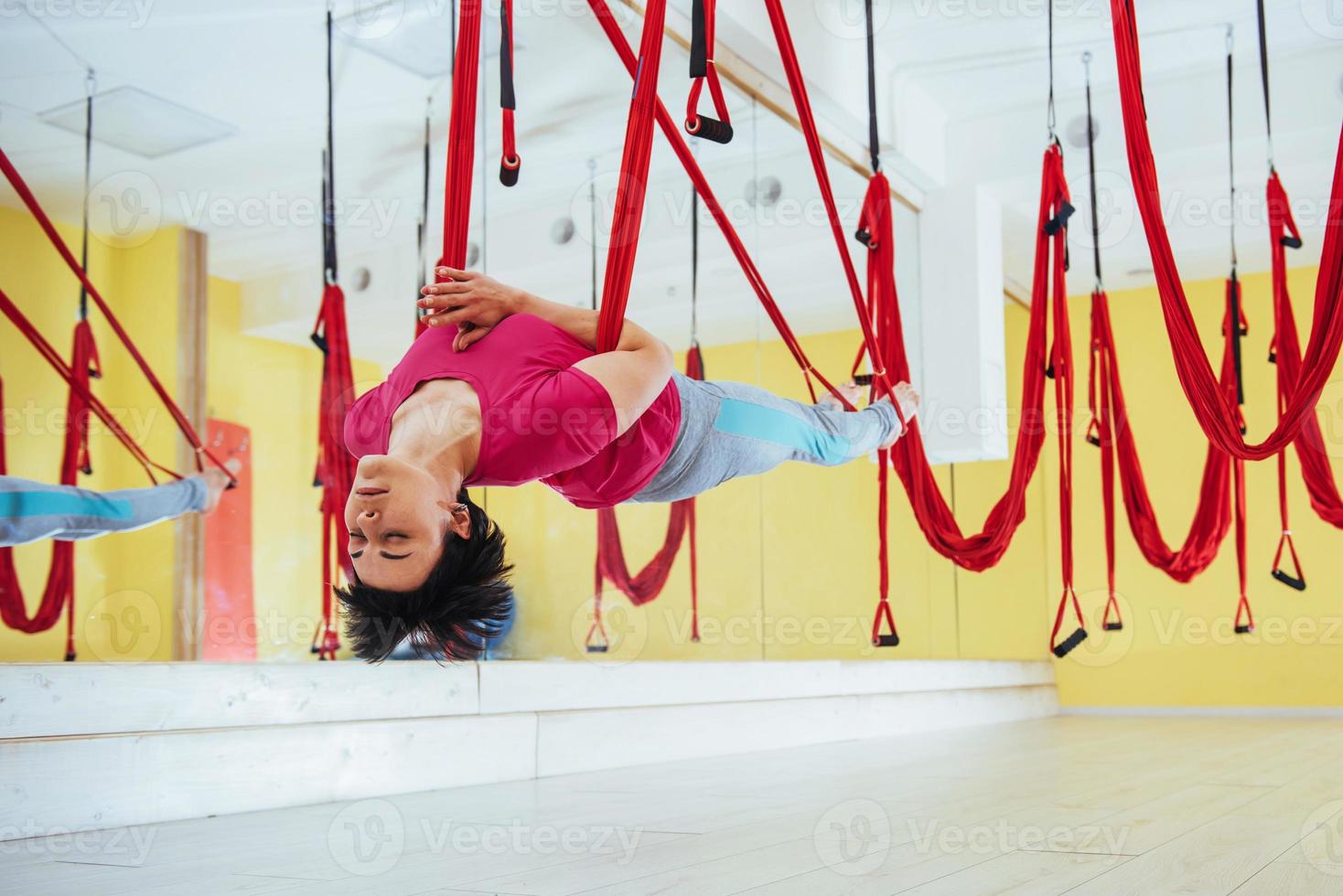 jonge mooie vrouw die yoga beoefent met een hangmat in de lichte studio. vliegen, fitness, stretch, balans, oefening. foto