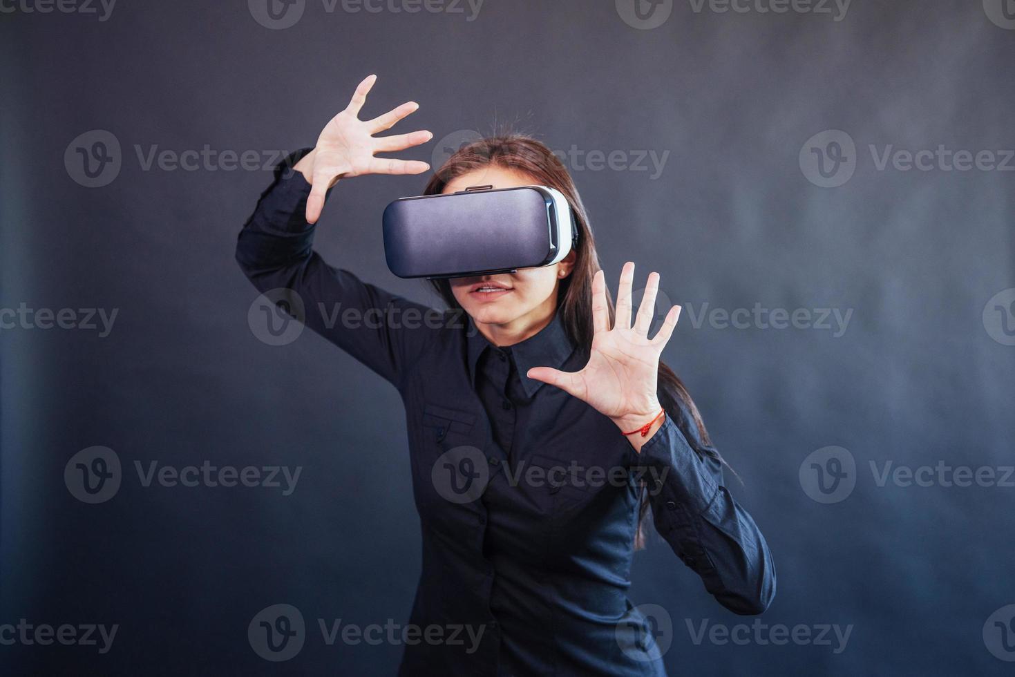 gelukkige vrouw op een zwarte achtergrond in de studio krijgt de ervaring van het gebruik van een vr-bril virtual reality-headset. foto