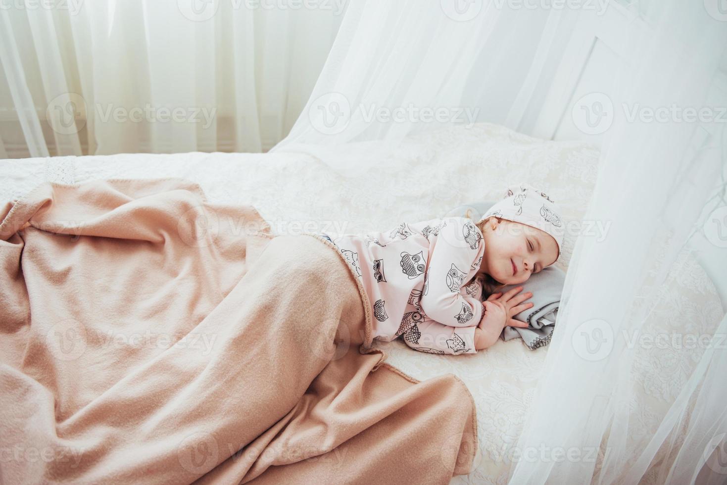 kind klein meisje slaapt in het bed foto
