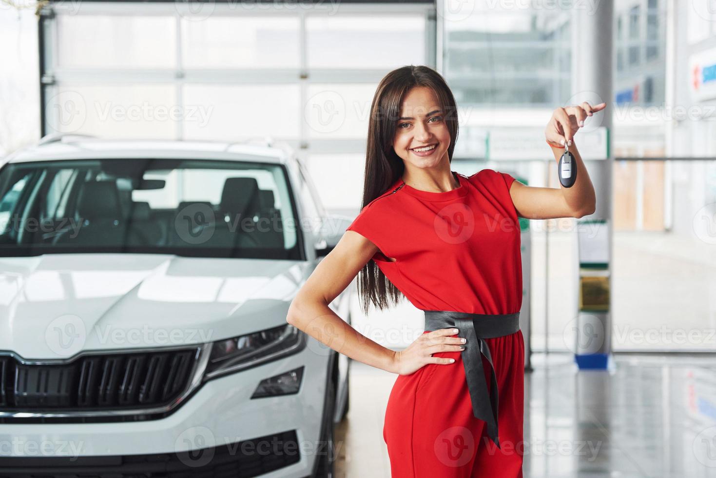 lachende autoverkoper die uw nieuwe autosleutels, dealerschap en verkoopconcept overhandigt. gelukkig meisje de koper foto