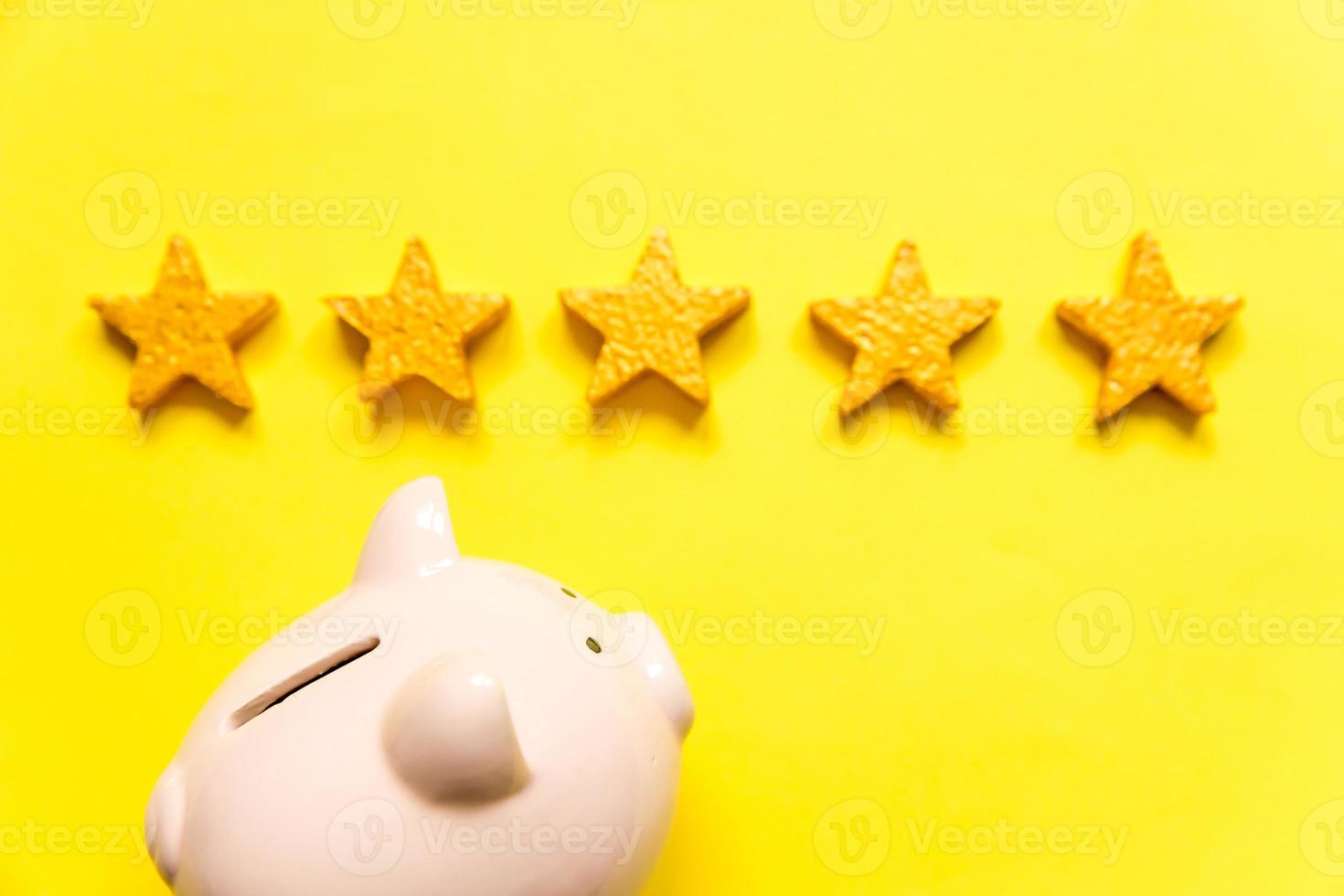eenvoudig minimaal ontwerp spaarvarken 5 gouden sterren geïsoleerd op gele achtergrond. rating van de bank. besparing investeringsbudget zakelijke pensioen financieel geld bankieren concept. plat lag bovenaanzicht kopieerruimte. foto