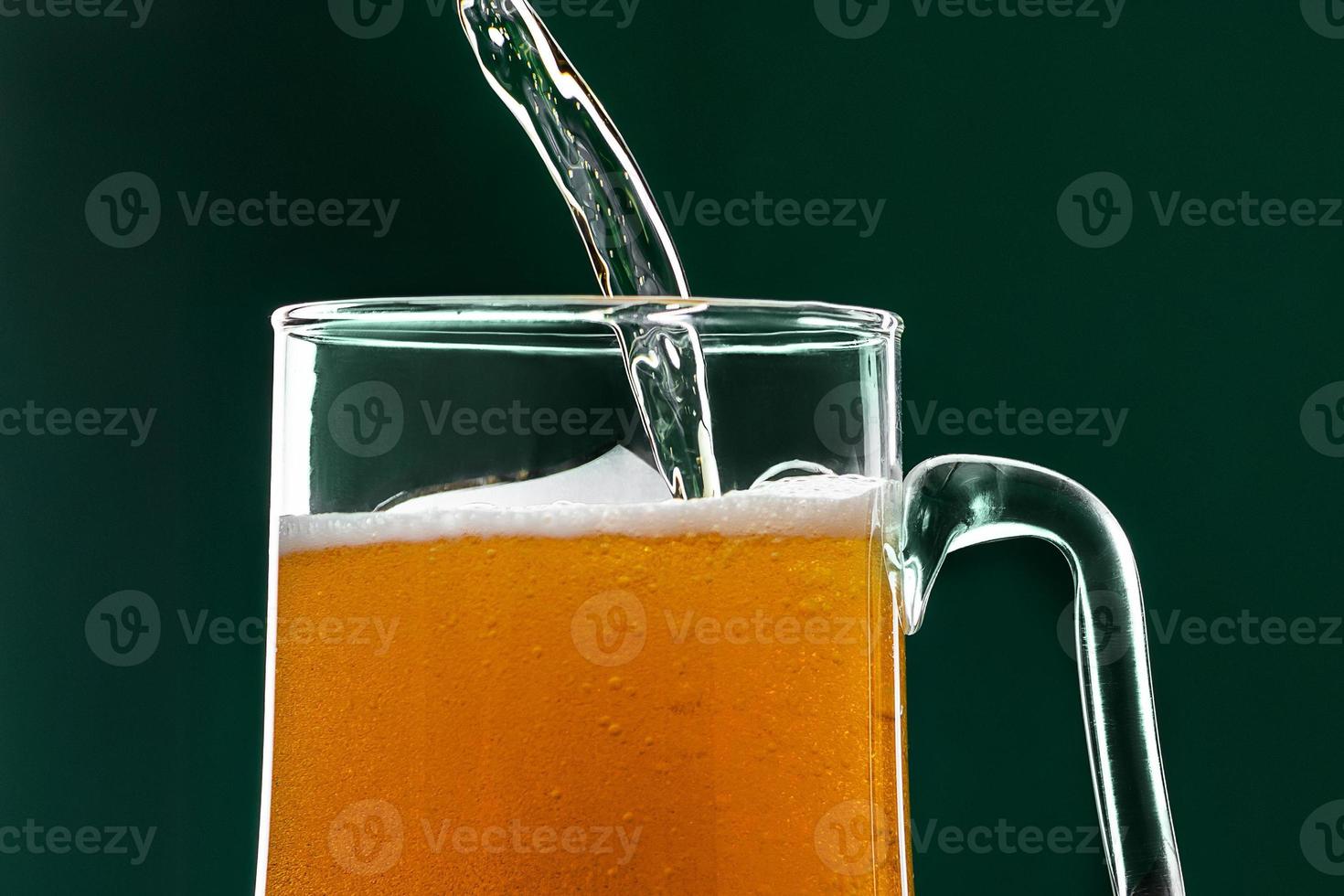 bier stroomt in een mok op een groene achtergrond. foto