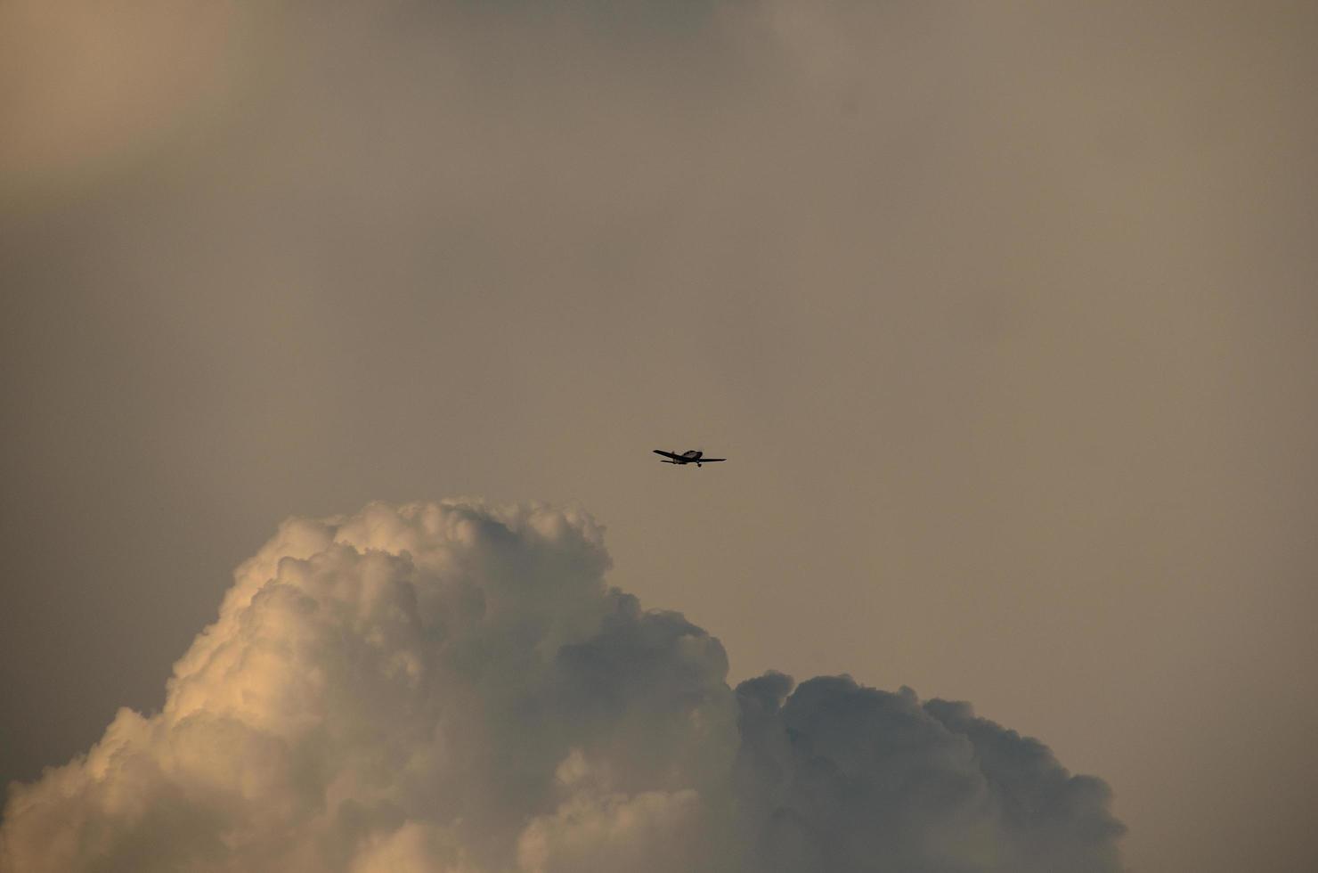 klein vliegtuig en grotere wolk foto