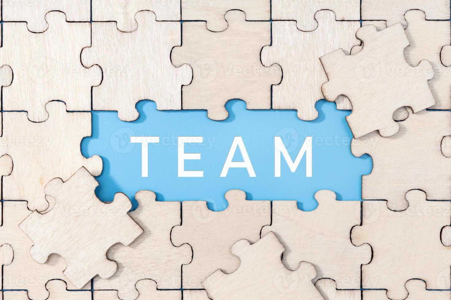 teamwoord op blauwe achtergrond omringd door puzzelstukjes foto