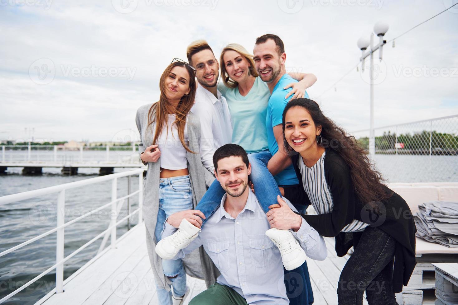 portret van een jong en gelukkig volk in rust op de pier. vrienden genieten van een spelletje op het meer. positieve emoties. foto