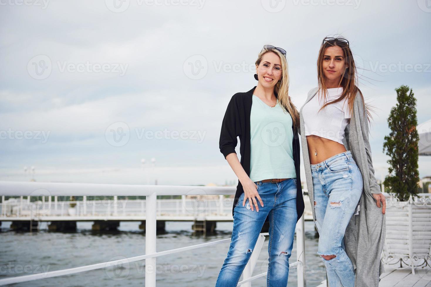 gelukkig jong meisje in stijlvolle kledingmerken op de pier bij het water foto