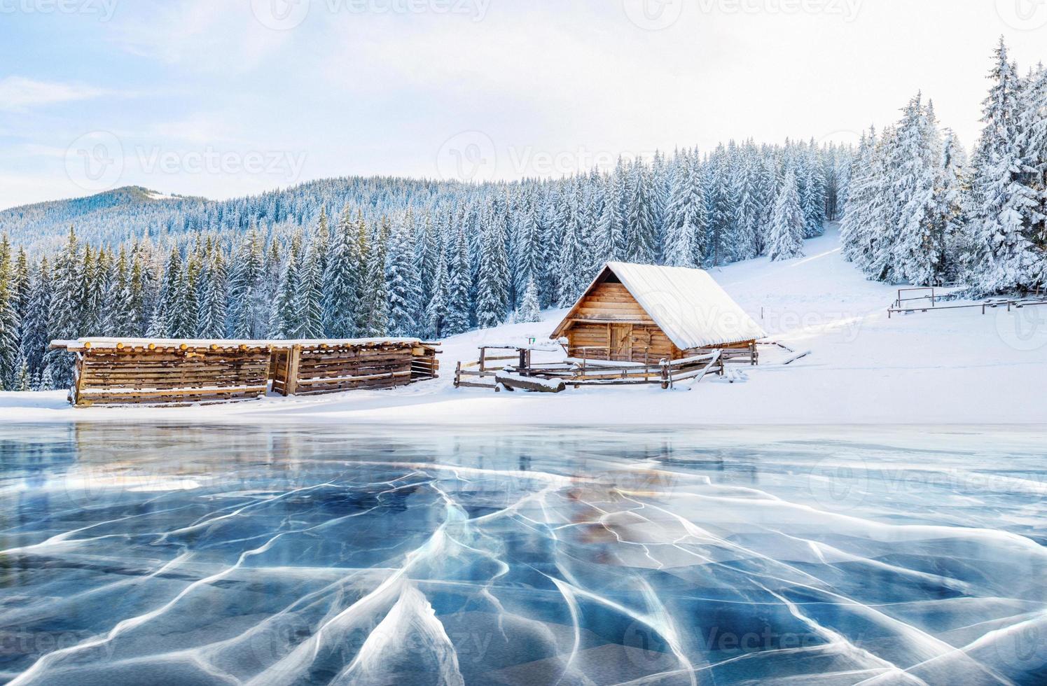 blauw ijs en scheuren op het oppervlak van het ijs. bevroren meer onder een blauwe hemel in de winter. hut in de bergen. mysterieuze mist. Karpaten. Oekraïne, Europa foto