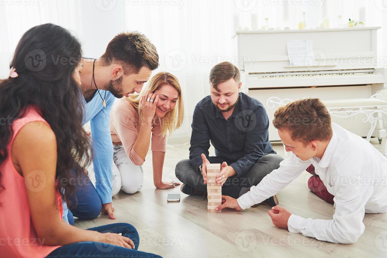 groep creatieve vrienden zitten aan houten tafel. mensen die plezier hebben tijdens het spelen van een bordspel foto