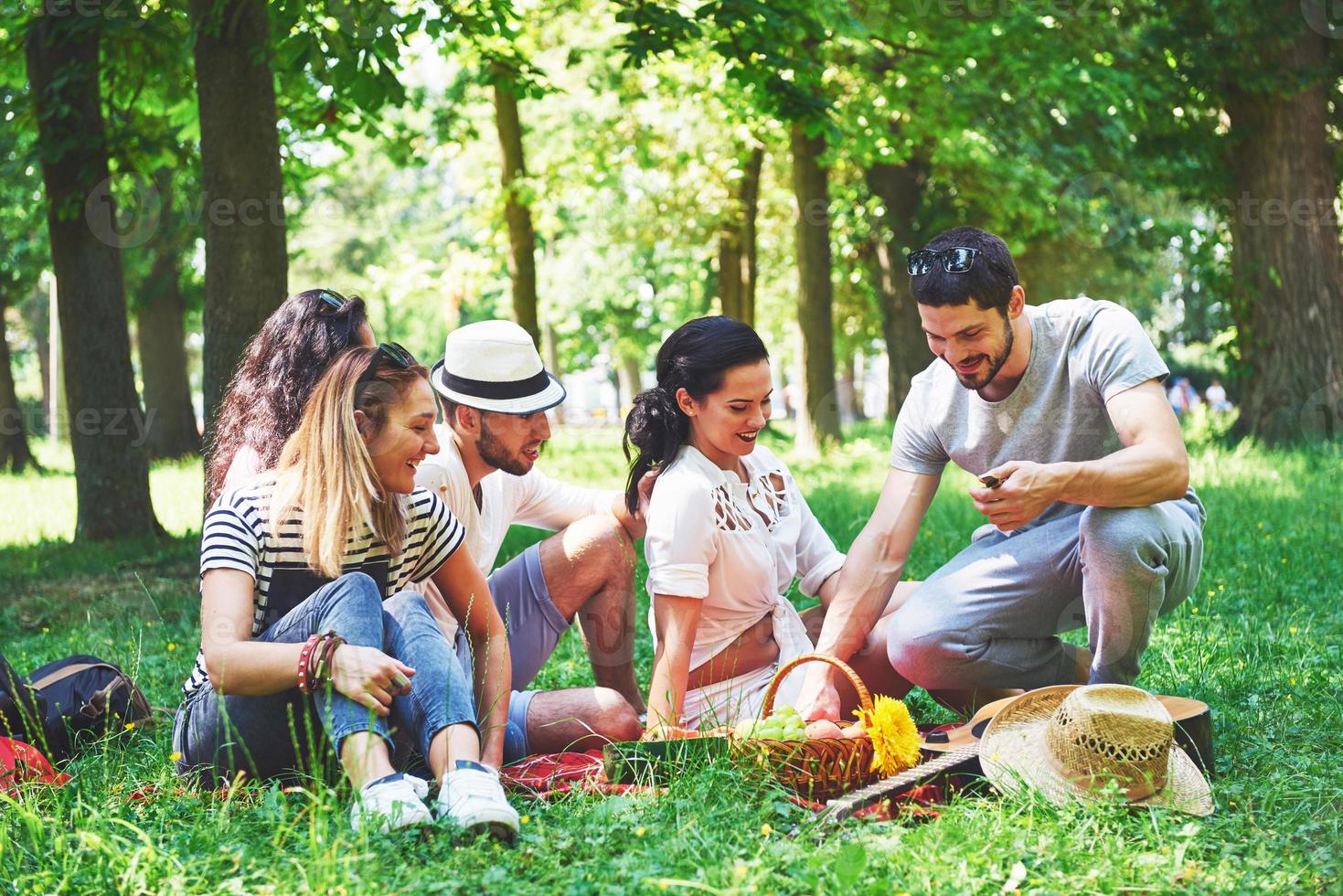 groep vrienden die op een zonnige dag picknicken in een park - mensen die rondhangen, plezier hebben tijdens het grillen en ontspannen foto