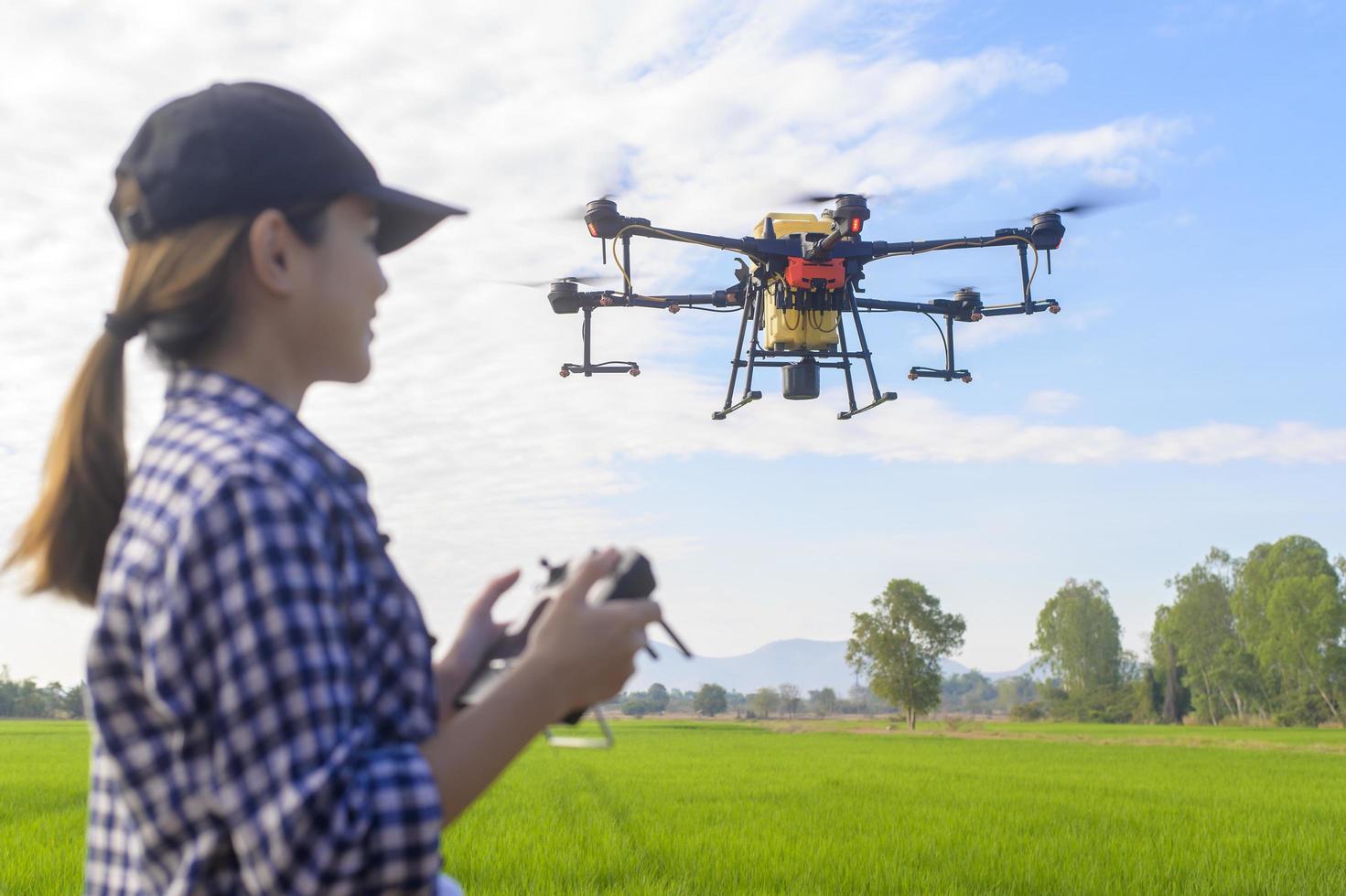 jonge slimme boer die drones bestuurt die kunstmest en pesticiden over landbouwgrond sproeien, geavanceerde technologische innovaties en slimme landbouw foto