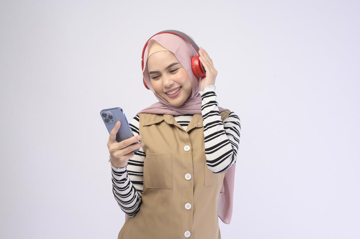 jonge mooie moslimvrouw die hoofdtelefoon op witte achtergrond draagt foto