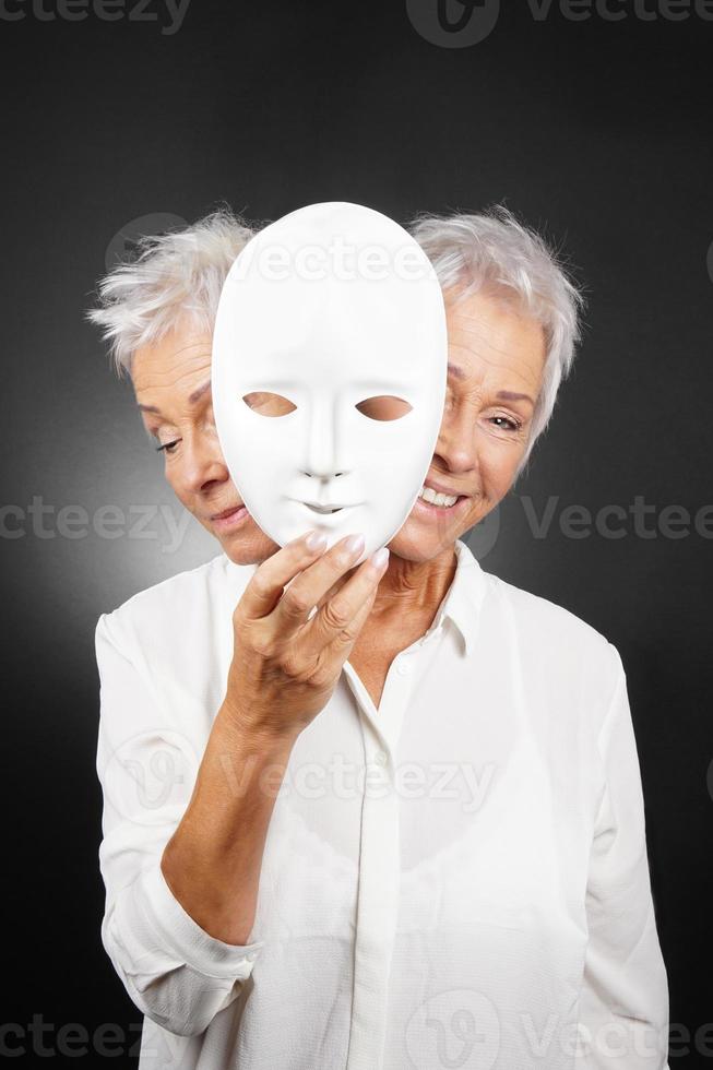 oudere vrouw verbergt blij en verdrietig gezicht achter masker foto