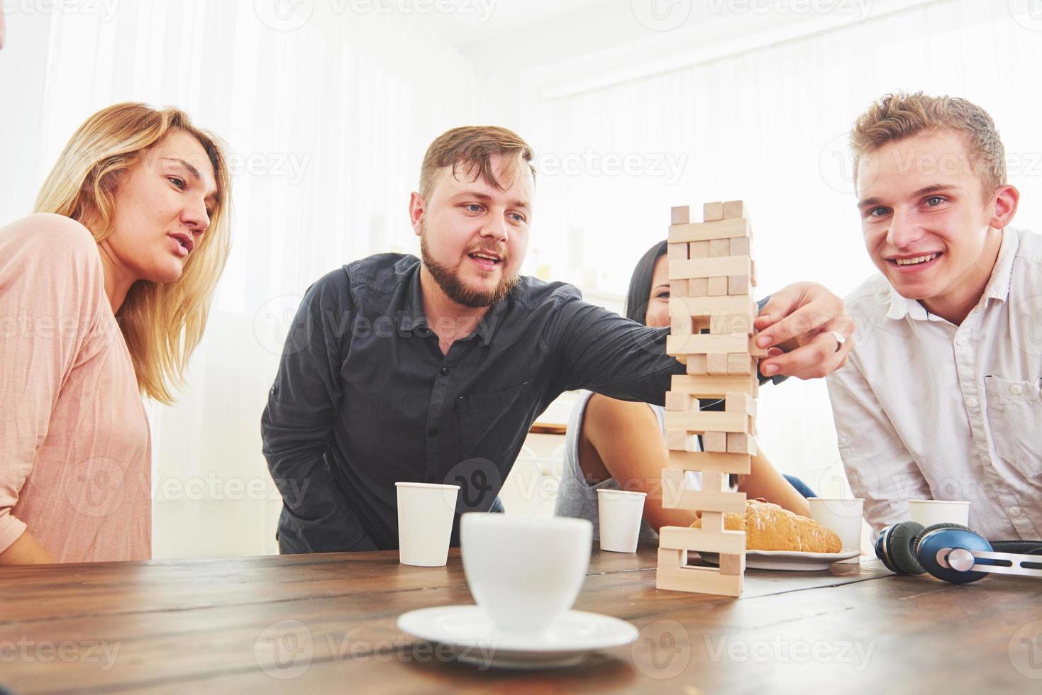 groep creatieve vrienden zitten aan houten tafel. mensen die plezier hebben tijdens het spelen van een bordspel foto