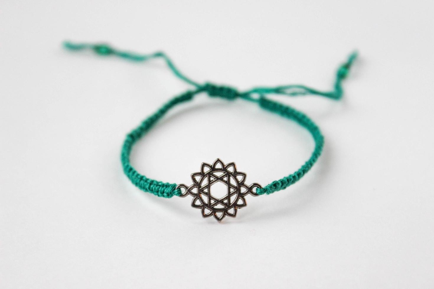 groene gevlochten armband met chakra anahatha op witte achtergrond foto