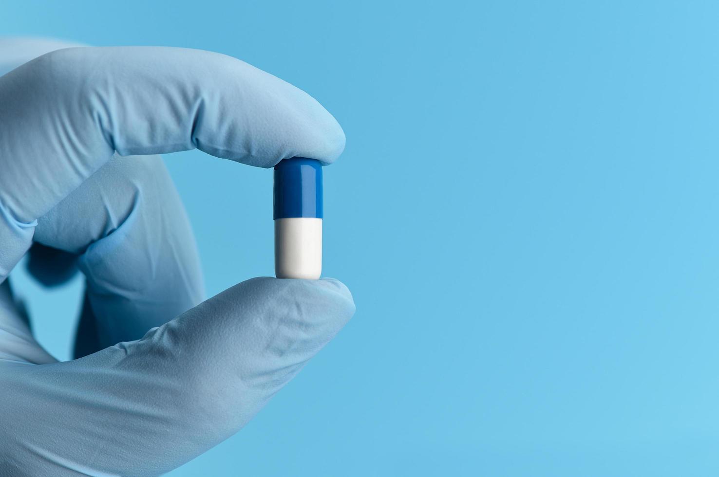 close-up shot van capsule pil in de hand van de verpleegster op blauwe achtergrond. foto
