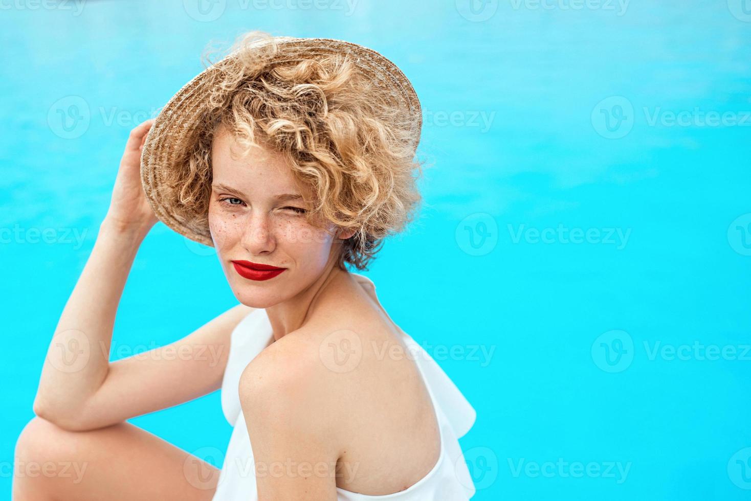 mooie lachende roodharige vrouw portret zittend bij het zwembad of aan zee in de zomerdag. zomer, relax, wellness, reizen, recreatieconcept foto