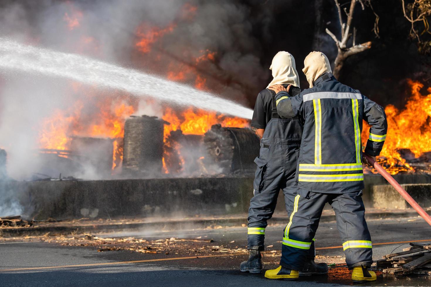 brandweerman spuit water uit grote waterslang om brand te voorkomen foto