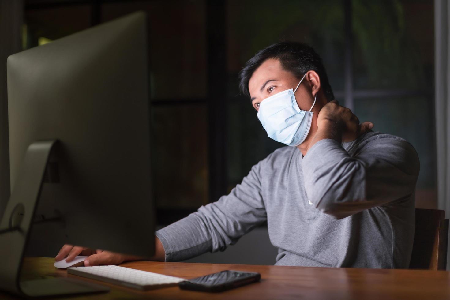 man met preventief masker en 's nachts thuiswerkend in situatie van corona-virusziekte. werk vanuit huis en gezond concept foto