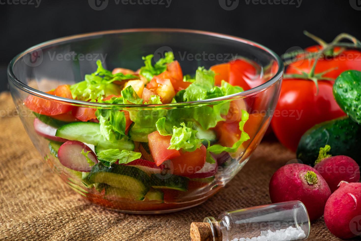 verse groentesalade in een glazen kom op donkere achtergrond. foto