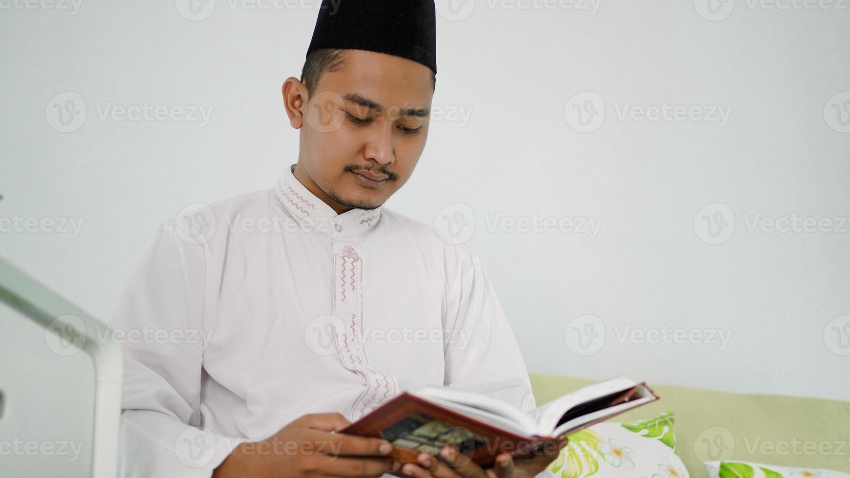 portret van een aziatische moslimman die thuis de heilige koran leest foto