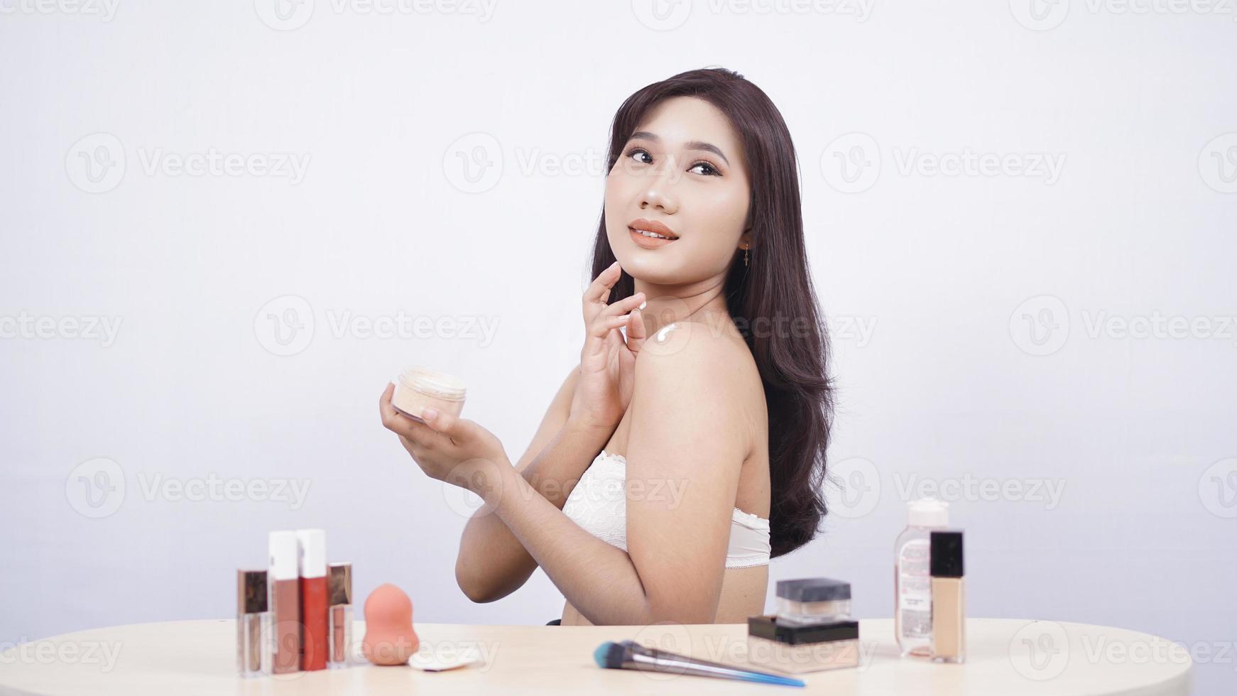 mooie Aziatische glimlach die make-up doet die op witte achtergrond wordt geïsoleerd foto