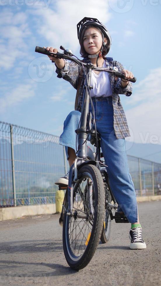 jonge aziatische vrouw pauzeert de fiets voordat ze naar het werk gaat foto