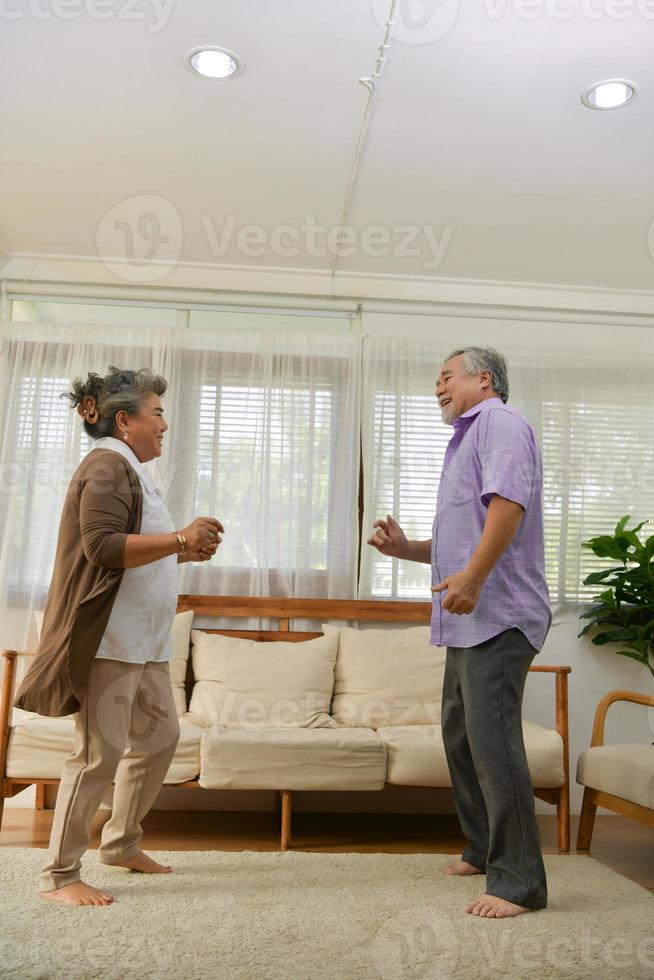 tijd samen doorbrengen thuis, een ouder Aziatisch stel dat plezier heeft met dansen in de woonkamer. foto