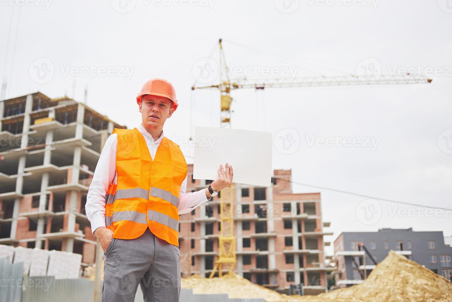 architectuur en huisvernieuwingsconcept - man in helm en handschoenen met blauwdruk in fabriek foto