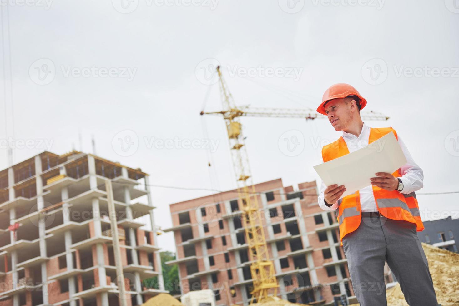 architectuur en huisvernieuwingsconcept - man in helm en handschoenen met blauwdruk in fabriek foto