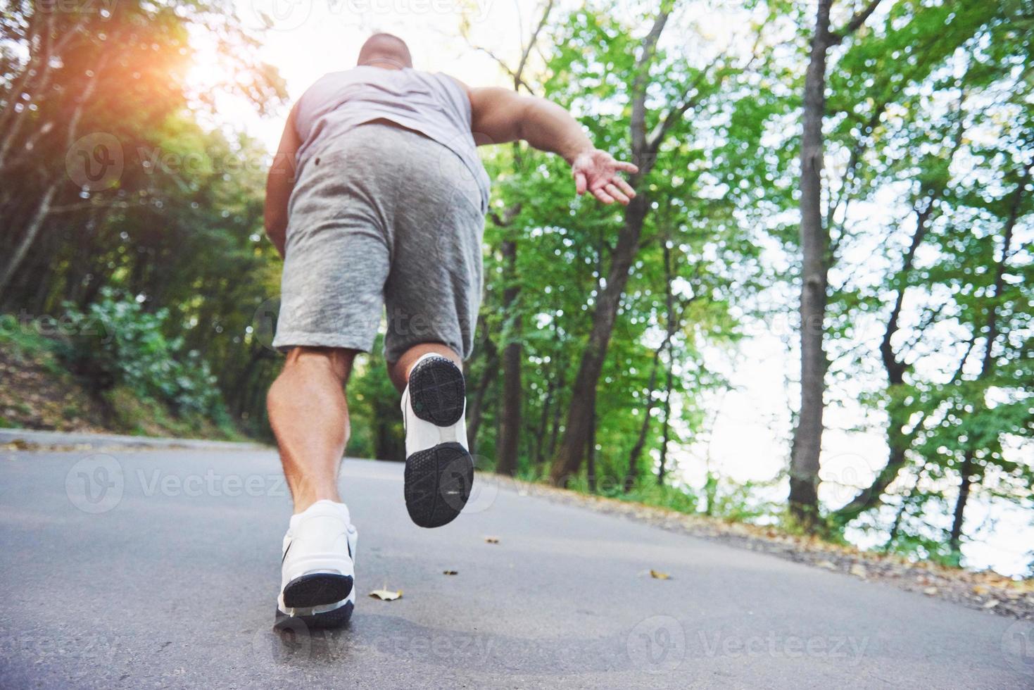 outdoor langlaufen in concept voor sporten, fitness en een gezonde levensstijl. close-up van de voeten van een jonge hardloper die langs de weg in het park loopt foto