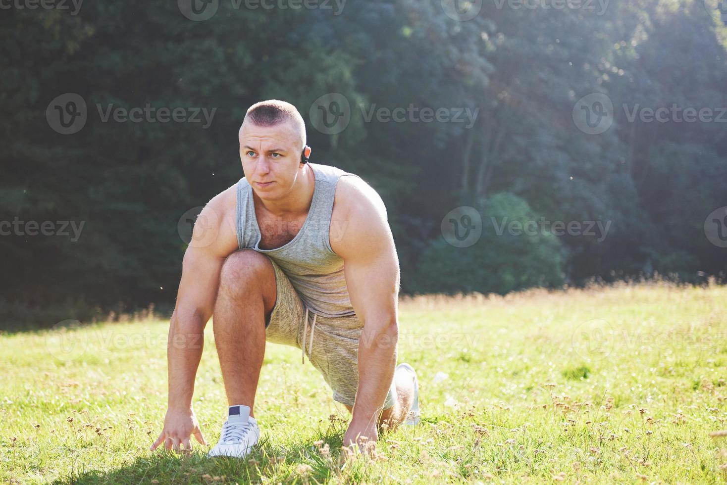 een jonge sportman die zich klaarmaakt voor atletische en fitnesstraining buitenshuis. sport, oefening, fitness, training. gezonde levensstijl foto