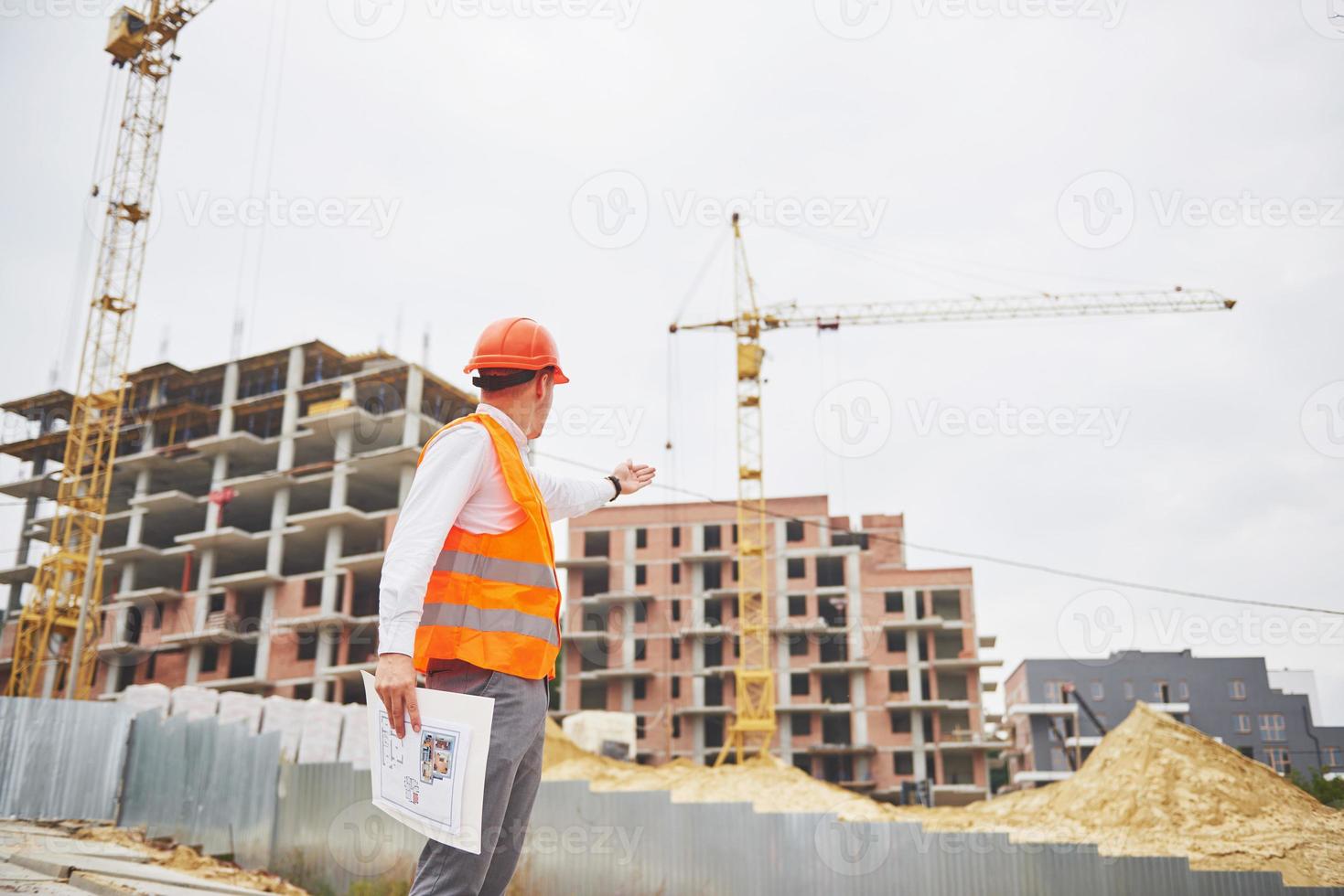 architectuur en huisvernieuwingsconcept - man in helm en handschoenen met blauwdruk in fabriek foto