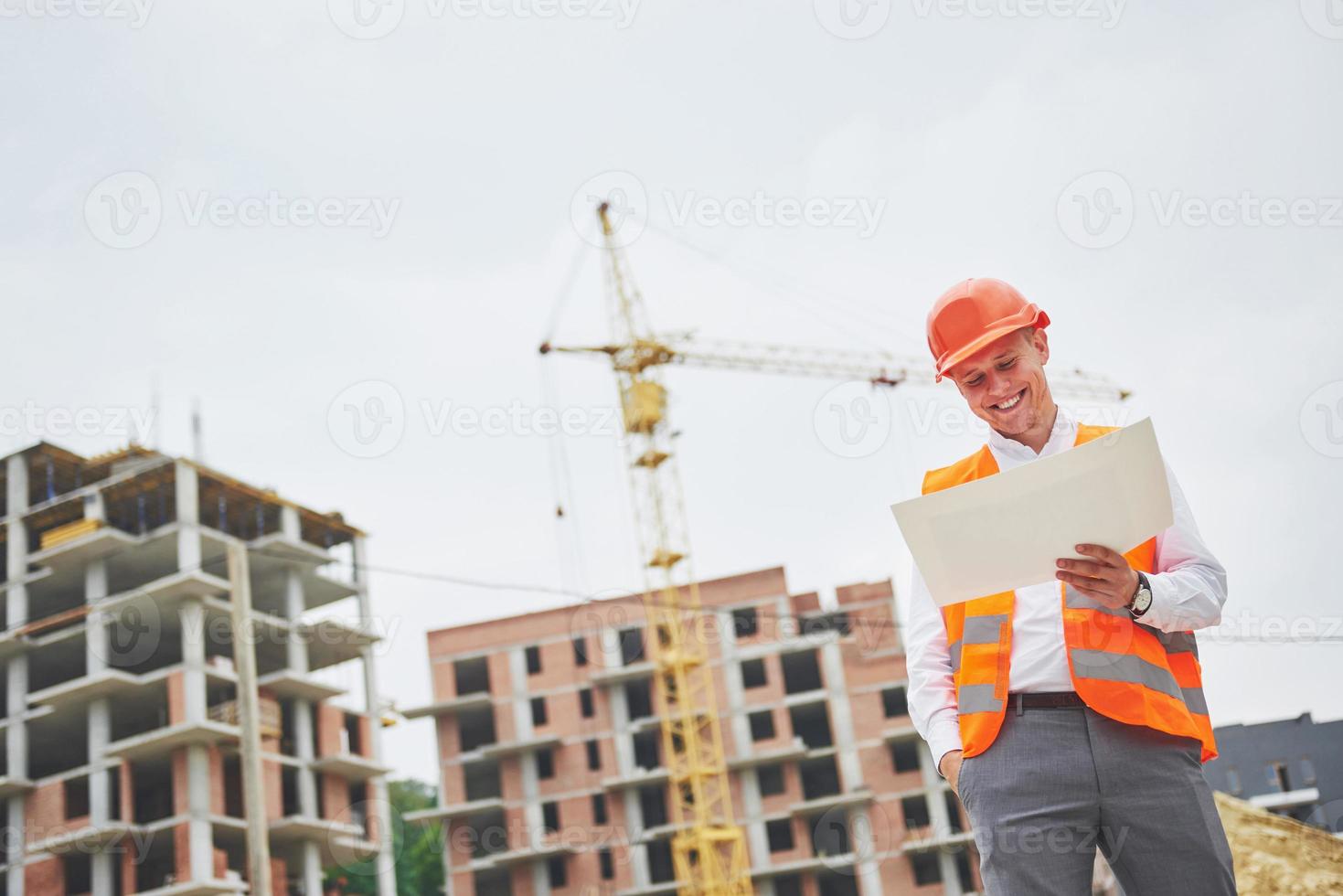 architectuur en huisvernieuwingsconcept - man in helm en handschoenen met blauwdruk in fabriek foto