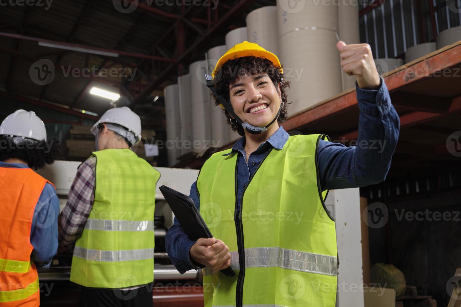 portret van veiligheidsuniform vrouwelijke ingenieur werknemer en helm met tablet kijkt naar camera, gelukkige glimlach, steek een vuist op en vrolijk, succes in de industrie, prestatie in de papierfabriek. foto