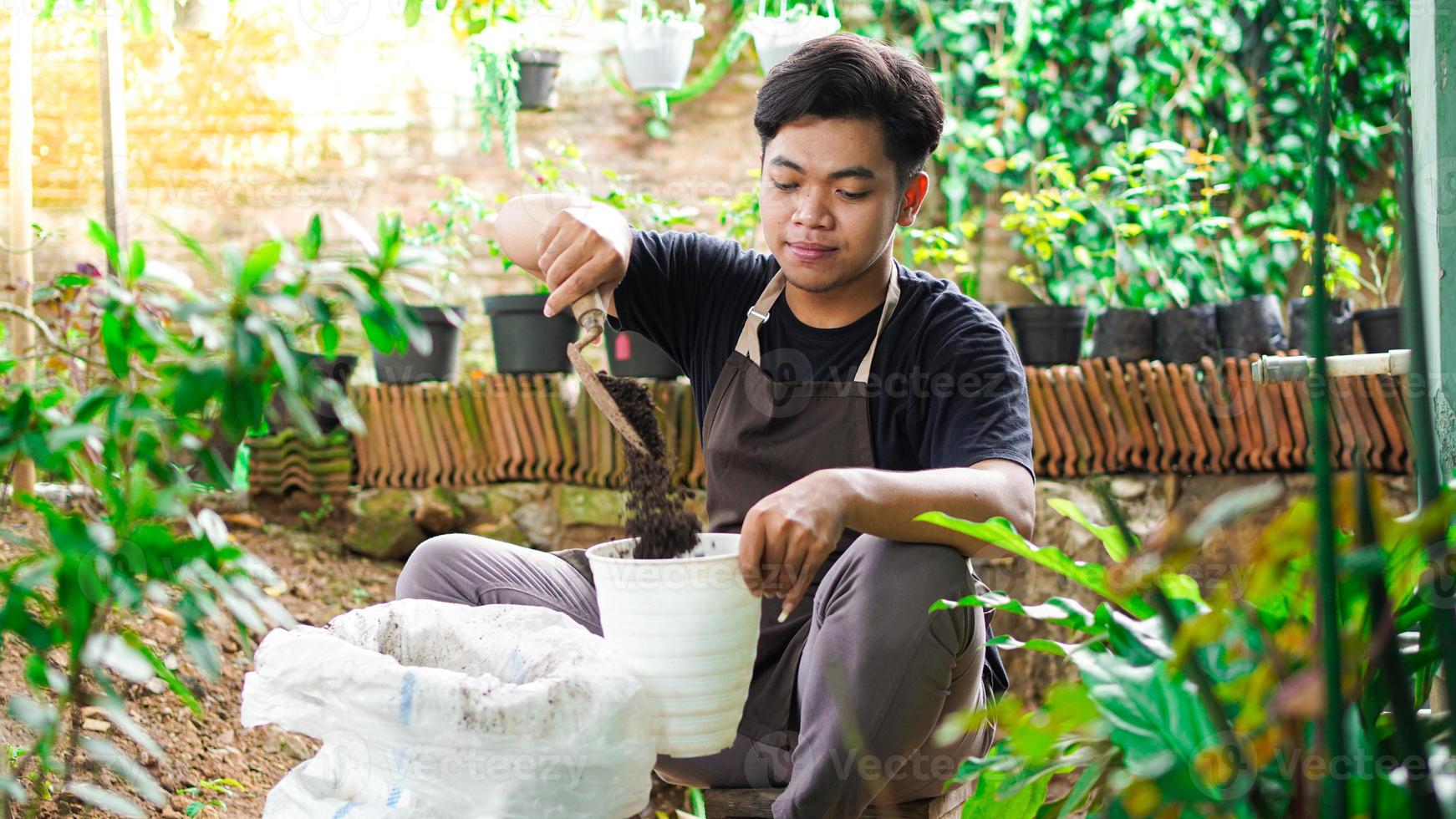 aziatische man bereidt een plek voor om te planten met pot en aarde foto