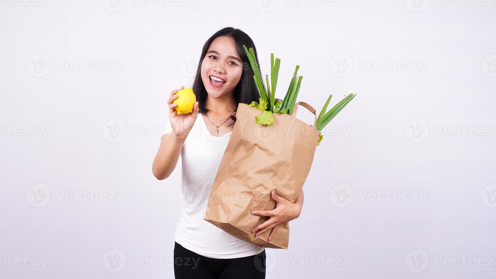 mooie aziatische vrouw met papieren zak verse groenten en met verse citroen foto