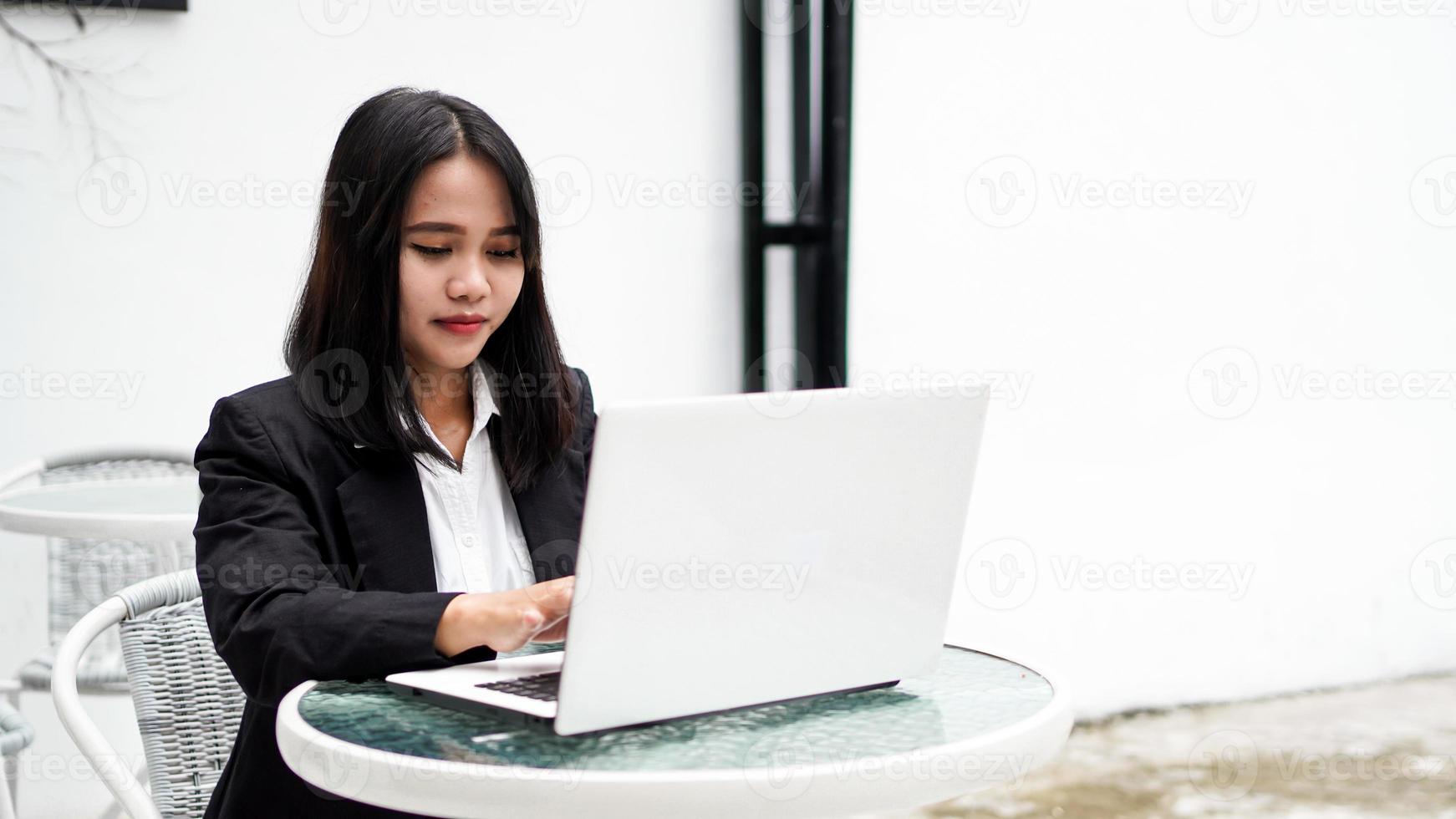 Aziatische jonge zakenvrouw die op de computer op kantoor werkt foto
