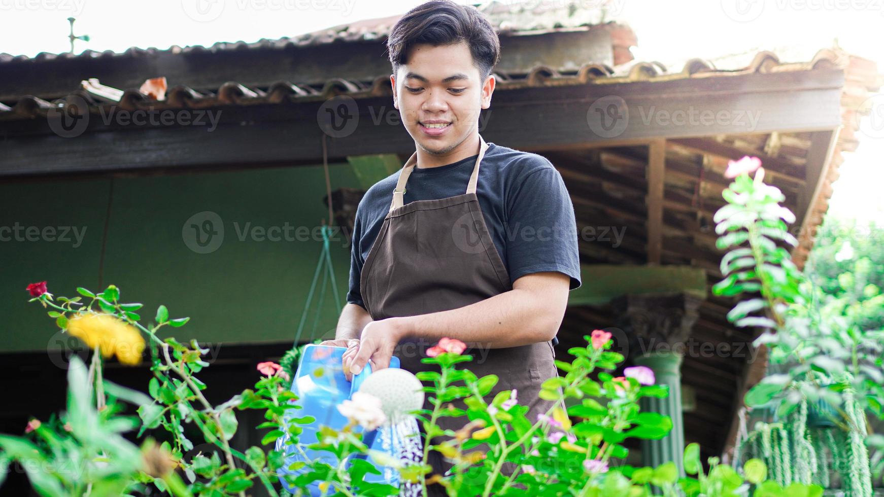 aziatische man die zorgt voor het water geven van de bloem in de tuin foto