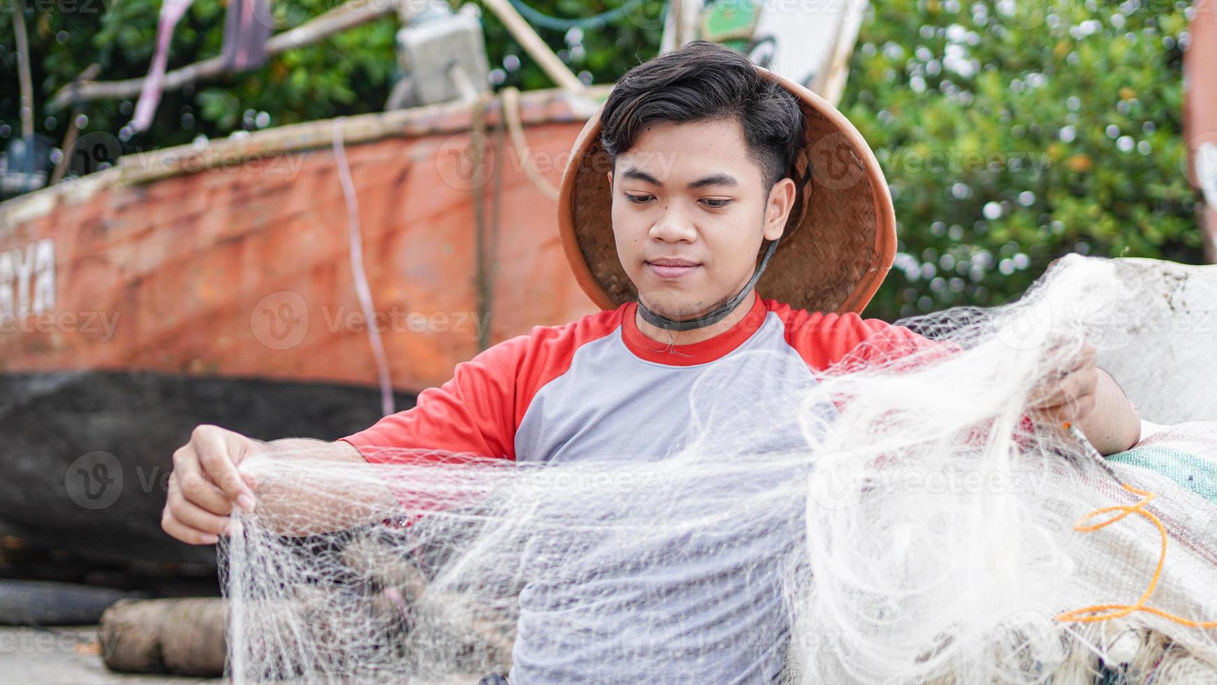 portret van een jonge mannelijke visser die een visnet op het strand voorbereidt foto
