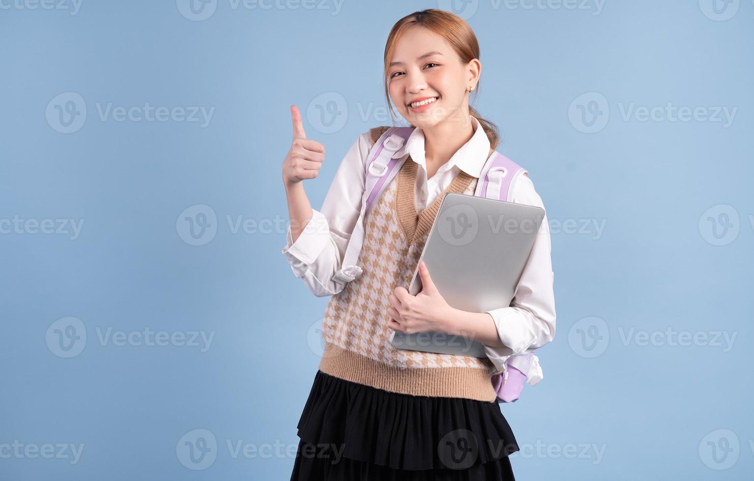 jong Aziatisch middelbare schoolmeisje op blauwe achtergrond foto