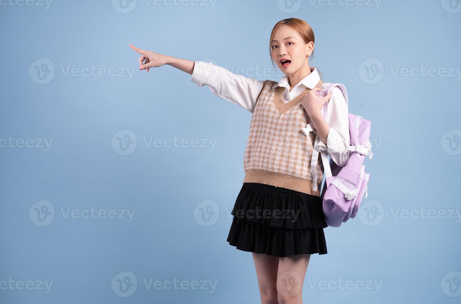 jong Aziatisch middelbare schoolmeisje op blauwe achtergrond foto