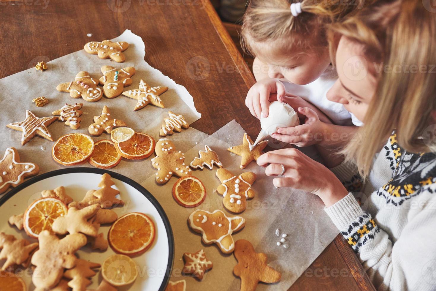 moeder en dochter versieren het kerstkoekje met witte suiker foto