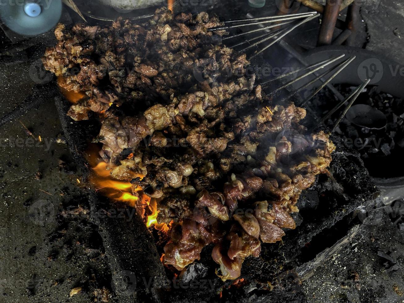 geit saté op rood vuur grillen door mensen. traditionele Indonesische gerechten gemaakt van schapenvlees. foto