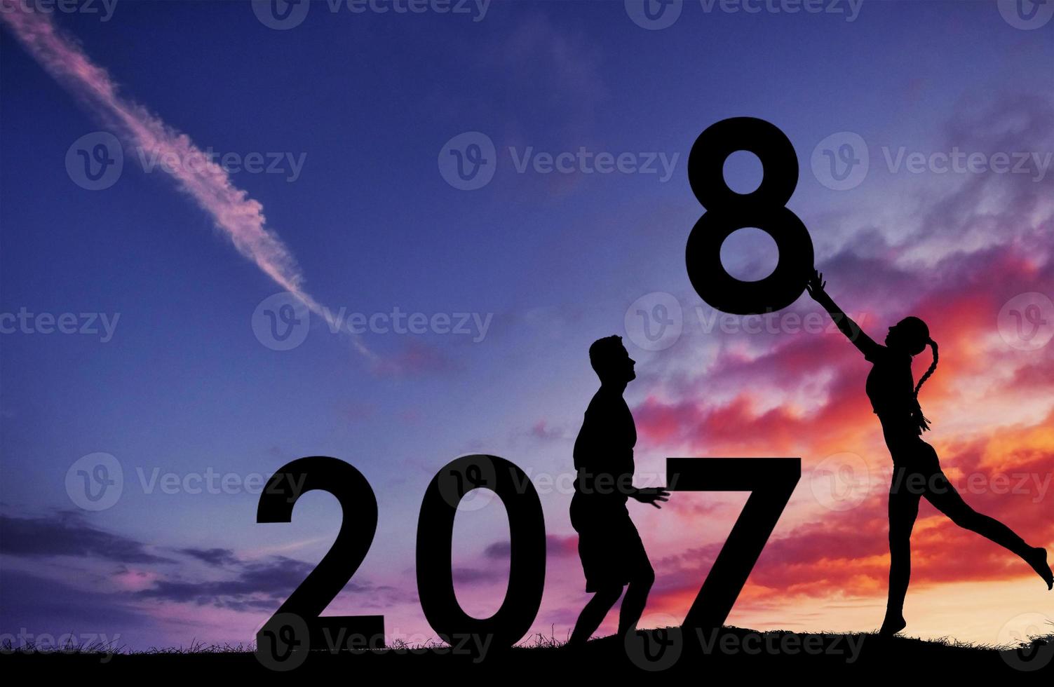 silhouet van de man en het meisje die de nummers van het nieuwe jaar in de zonsondergang houden. concept van vervanging 2017 tot 2018 foto