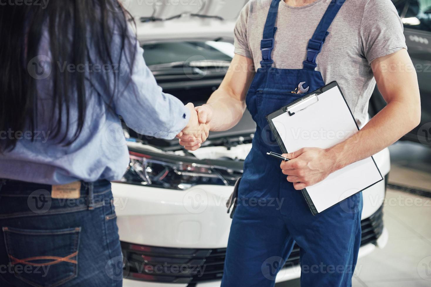 man automonteur en vrouw klant maken een overeenkomst over de reparatie van de auto foto